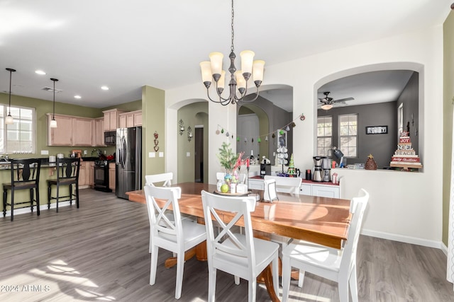 dining area with plenty of natural light, ceiling fan with notable chandelier, and light hardwood / wood-style flooring