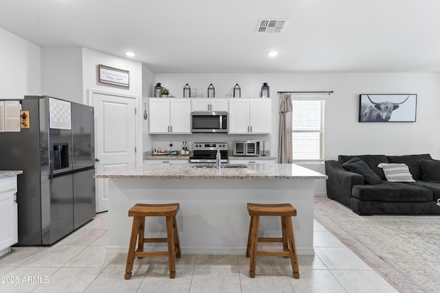16617 W Desert Mirage Dr, Surprise, AZ 85388 - kitchen with appliances with stainless steel finishes, a sink, a breakfast bar, white cabinets, and light stone counters