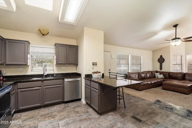 kitchen with kitchen peninsula, sink, dark stone counters, a kitchen bar, and stainless steel appliances