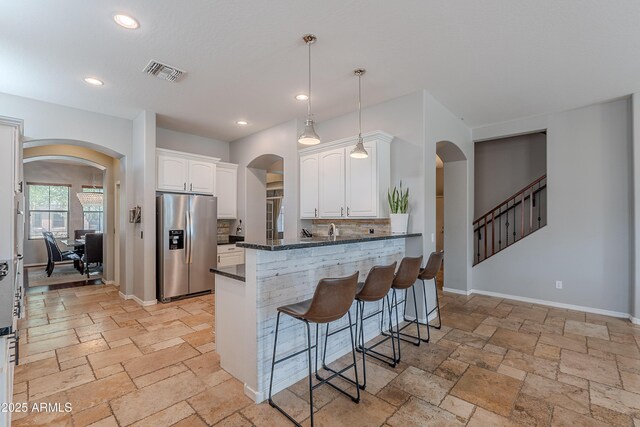 2735 E Flower Ct, Gilbert, AZ 85298 - kitchen featuring stainless steel fridge, arched walkways, white cabinetry, stone tile floors, and a breakfast bar area