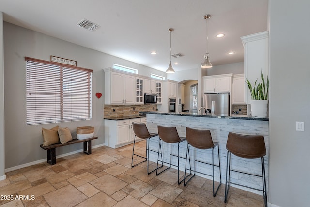 2735 E Flower Ct, Gilbert, AZ 85298 - kitchen with stainless steel appliances, a kitchen breakfast bar, decorative backsplash, arched walkways, and a peninsula