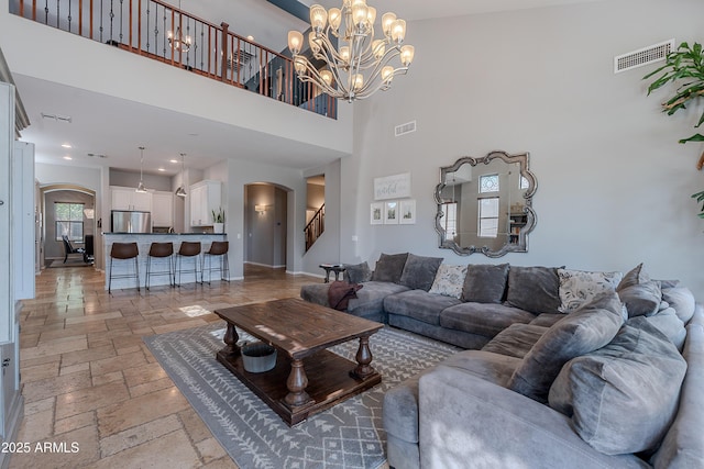 2735 E Flower Ct, Gilbert, AZ 85298 - living room featuring arched walkways, stone tile flooring, a high ceiling, stairway, and a chandelier