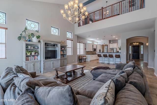 2735 E Flower Ct, Gilbert, AZ 85298 - living room featuring a towering ceiling, a chandelier, arched walkways, and baseboards