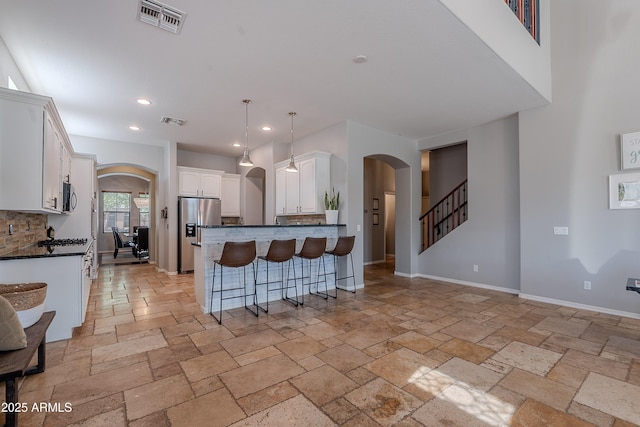 2735 E Flower Ct, Gilbert, AZ 85298 - kitchen featuring stainless steel appliances, arched walkways, dark countertops, recessed lighting, and stone tile flooring