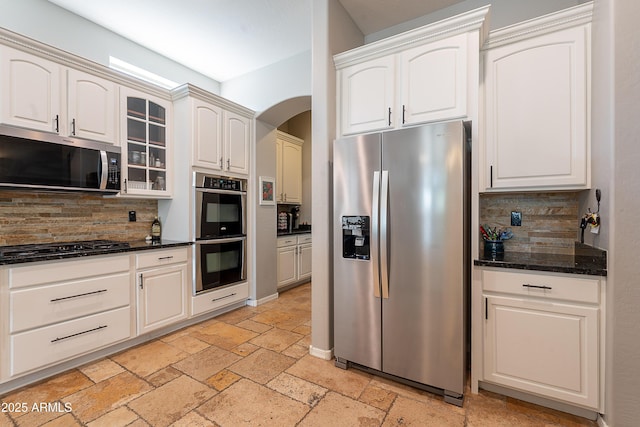 2735 E Flower Ct, Gilbert, AZ 85298 - kitchen with stainless steel appliances, backsplash, stone tile flooring, arched walkways, and glass insert cabinets