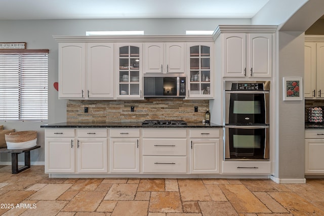 2735 E Flower Ct, Gilbert, AZ 85298 - kitchen featuring appliances with stainless steel finishes, backsplash, stone tile flooring, glass insert cabinets, and white cabinets