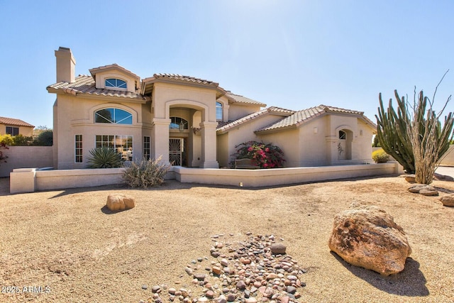 mediterranean / spanish-style house with a tile roof, a chimney, and stucco siding