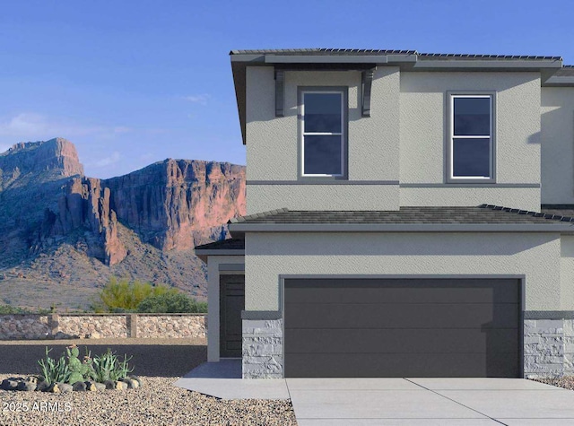 view of front of property with a mountain view, an attached garage, driveway, and stucco siding