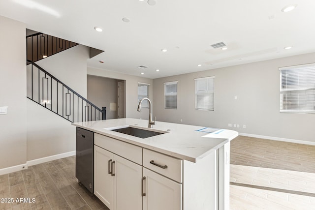 kitchen with wood finish floors, visible vents, a sink, baseboards, and dishwasher