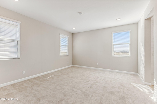 spare room featuring baseboards, plenty of natural light, and light colored carpet