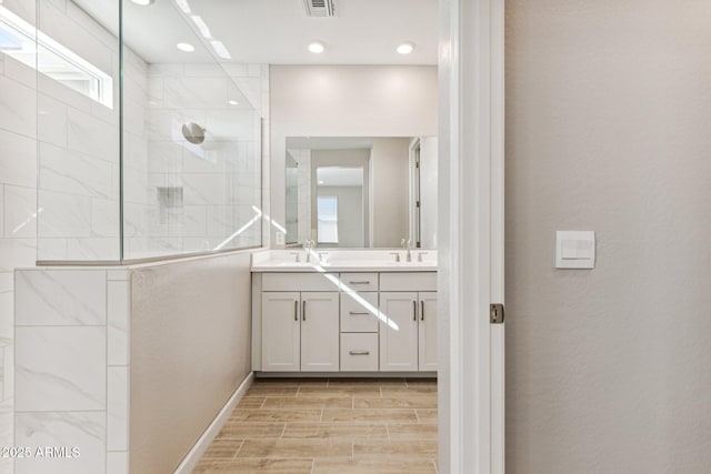 full bathroom with double vanity, walk in shower, wood tiled floor, and a sink