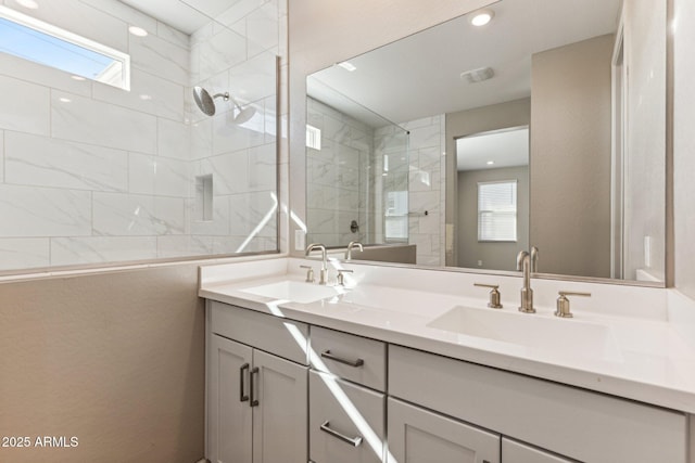 bathroom with a shower stall, double vanity, and a sink