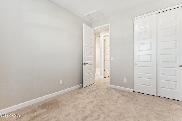 unfurnished bedroom with light carpet, visible vents, a closet, and baseboards