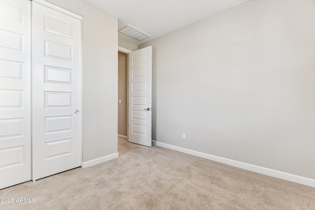 unfurnished bedroom with visible vents, baseboards, a closet, and light carpet