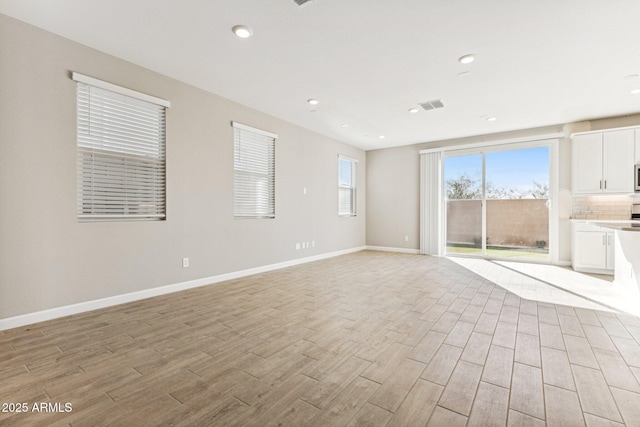 unfurnished living room featuring light wood-type flooring, visible vents, baseboards, and recessed lighting