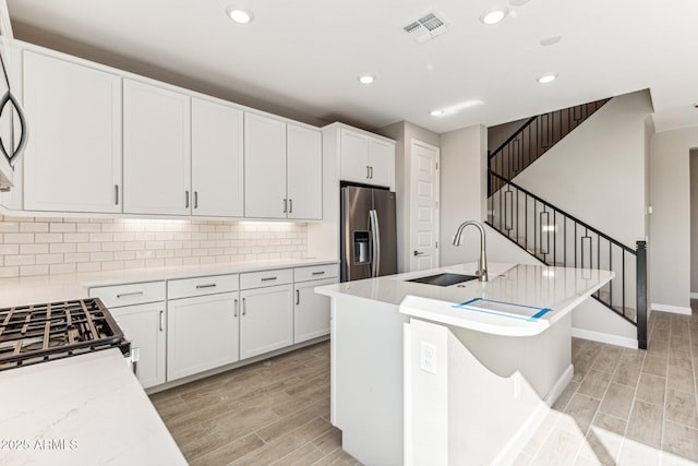 kitchen with a sink, stainless steel appliances, wood finish floors, and visible vents