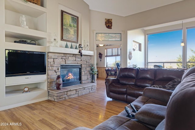 living room with built in features, light wood-type flooring, and a fireplace