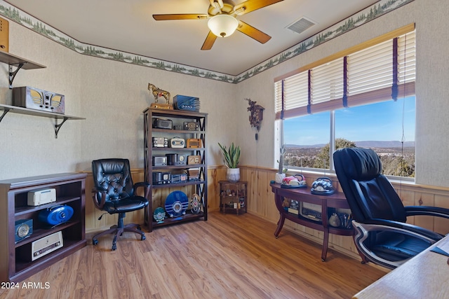 home office featuring ceiling fan, wood-type flooring, and wooden walls