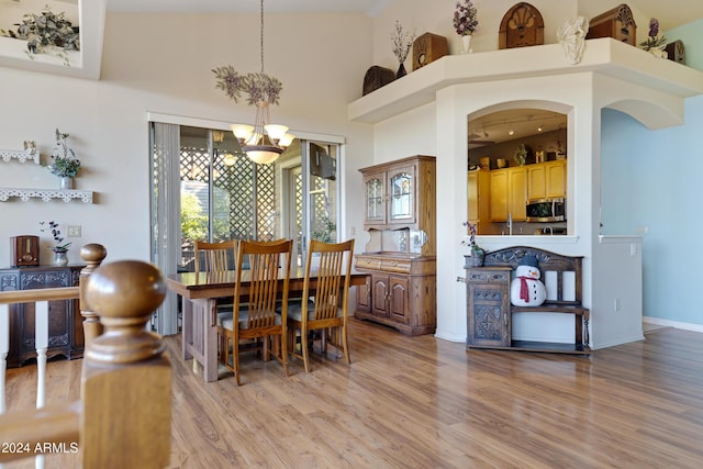 dining room featuring an inviting chandelier, high vaulted ceiling, and light hardwood / wood-style flooring