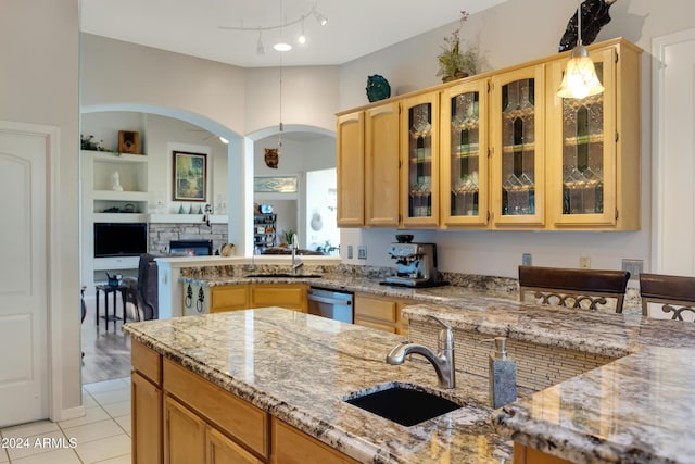 kitchen featuring light stone counters, light tile patterned floors, sink, and hanging light fixtures