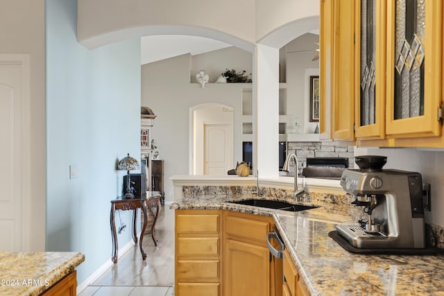 kitchen featuring sink, vaulted ceiling, ceiling fan, light stone countertops, and light brown cabinetry