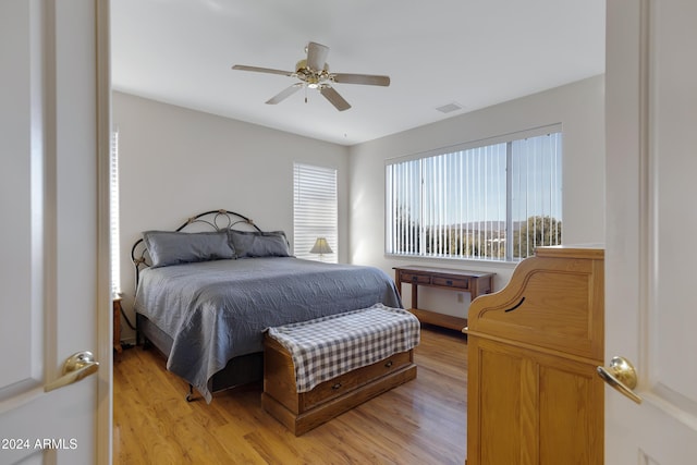 bedroom featuring ceiling fan, light hardwood / wood-style flooring, and multiple windows