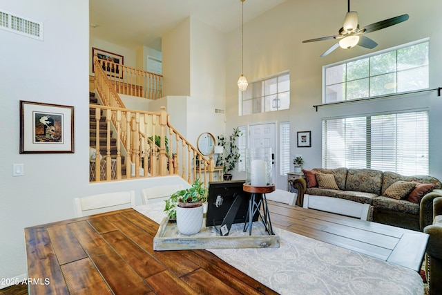 interior space with stairway, a ceiling fan, visible vents, and wood finished floors