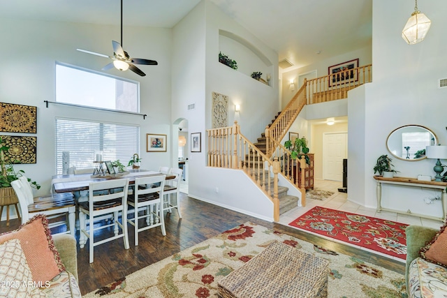 interior space featuring visible vents, arched walkways, a ceiling fan, wood finished floors, and stairs