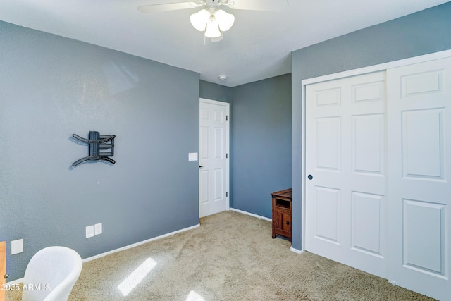 carpeted bedroom with a ceiling fan, a closet, and baseboards