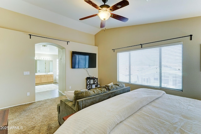 carpeted bedroom featuring arched walkways, ceiling fan, lofted ceiling, and ensuite bath