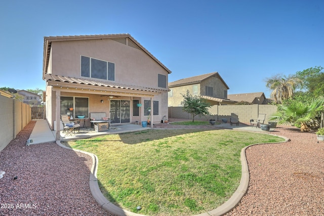 back of property with a patio, a fenced backyard, a ceiling fan, a yard, and stucco siding