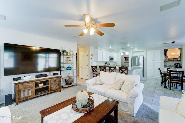 living area featuring arched walkways, light colored carpet, ceiling fan, and light tile patterned floors