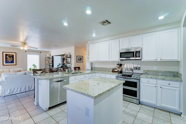 kitchen with visible vents, appliances with stainless steel finishes, open floor plan, a peninsula, and a sink