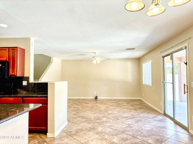 kitchen with light tile patterned floors, backsplash, dark stone countertops, and ceiling fan