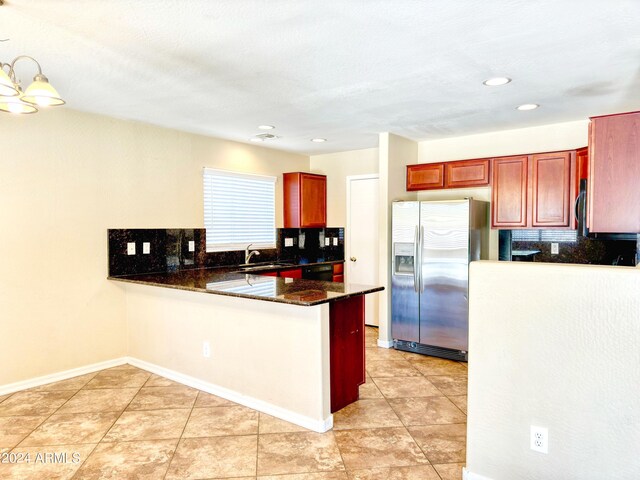 kitchen with decorative backsplash, stainless steel fridge with ice dispenser, light tile patterned floors, sink, and kitchen peninsula