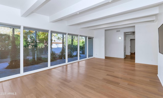 spare room featuring beamed ceiling and wood finished floors