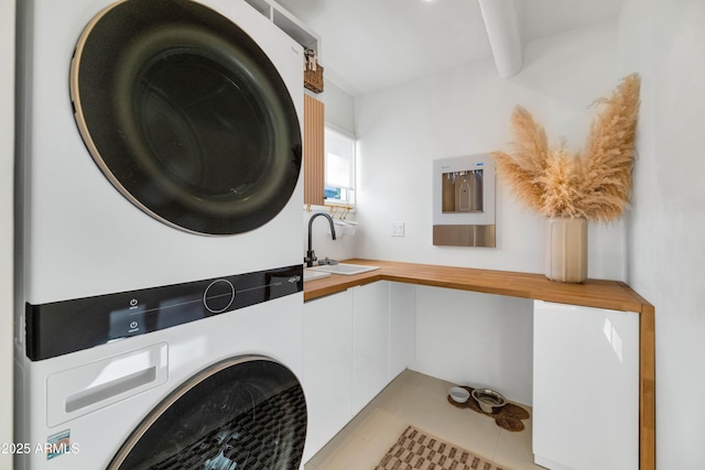 clothes washing area with a sink, stacked washer and clothes dryer, laundry area, and light tile patterned floors