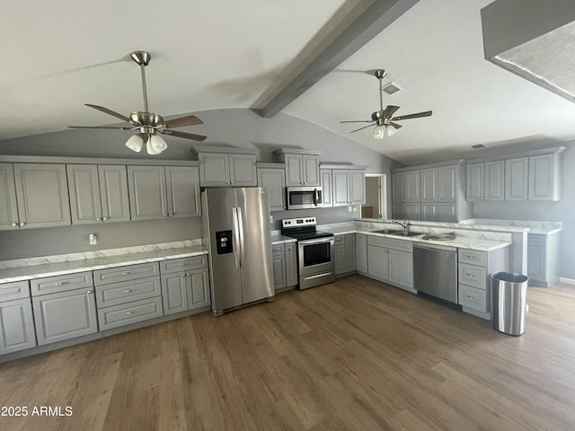 kitchen with vaulted ceiling with beams, gray cabinetry, ceiling fan, stainless steel appliances, and dark wood-type flooring