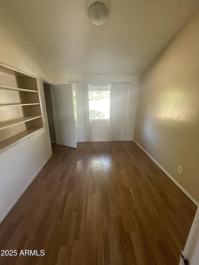 empty room with dark hardwood / wood-style flooring and built in features