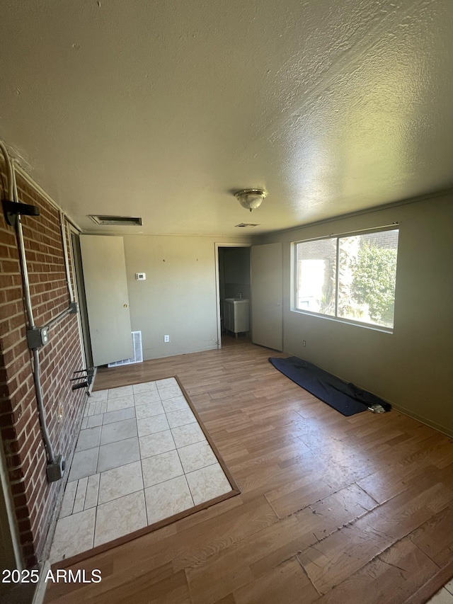 unfurnished room with a textured ceiling and light wood-type flooring