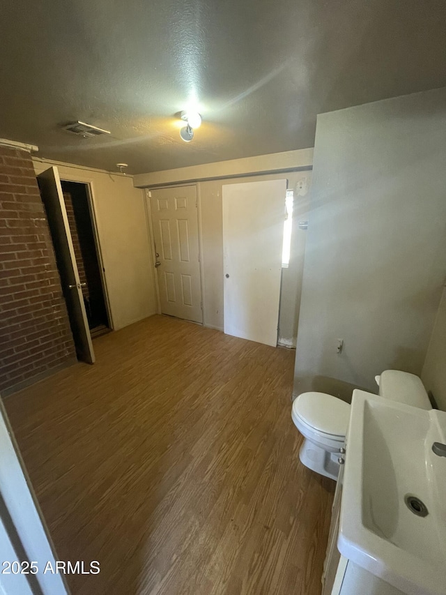 bathroom featuring sink, wood-type flooring, a textured ceiling, and brick wall