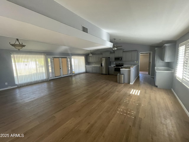 unfurnished living room with dark hardwood / wood-style flooring, vaulted ceiling, and ceiling fan