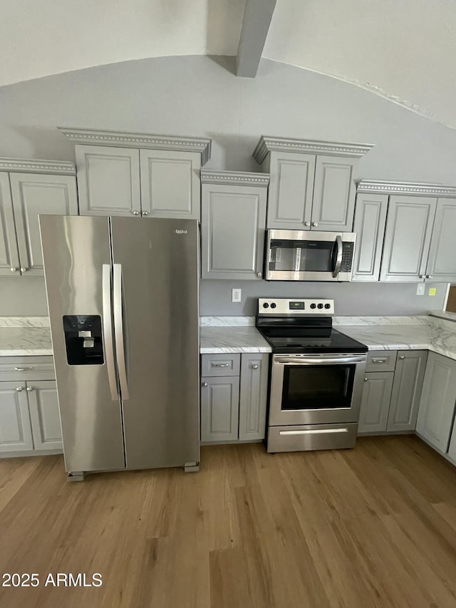 kitchen with gray cabinets, light hardwood / wood-style floors, lofted ceiling with beams, and appliances with stainless steel finishes