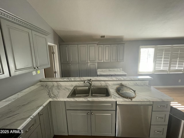 kitchen with sink, gray cabinets, light stone countertops, vaulted ceiling, and stainless steel dishwasher