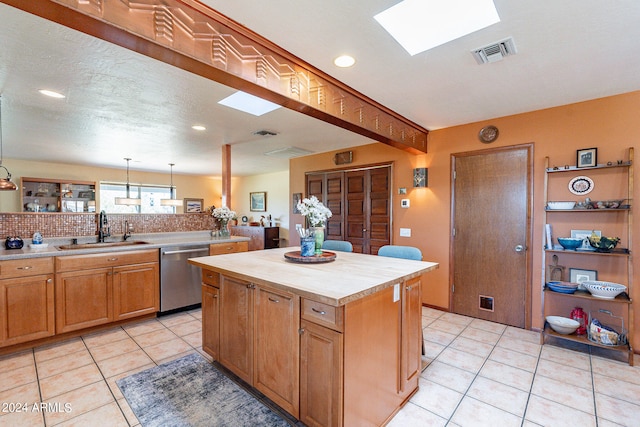 kitchen featuring a skylight, a kitchen island, stainless steel dishwasher, light tile floors, and sink