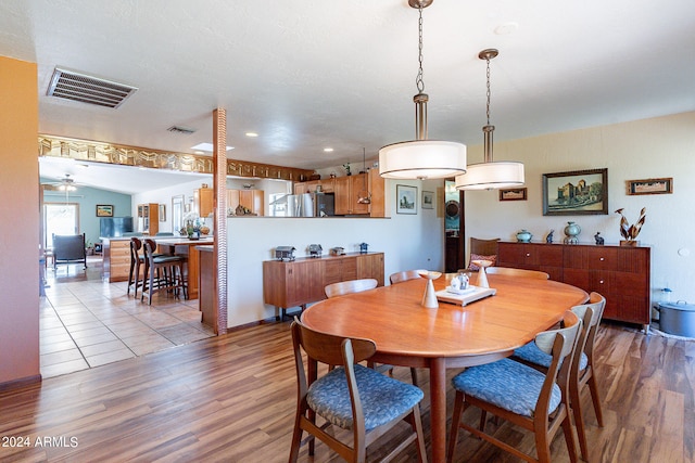 dining area with ceiling fan, lofted ceiling, and light hardwood / wood-style flooring