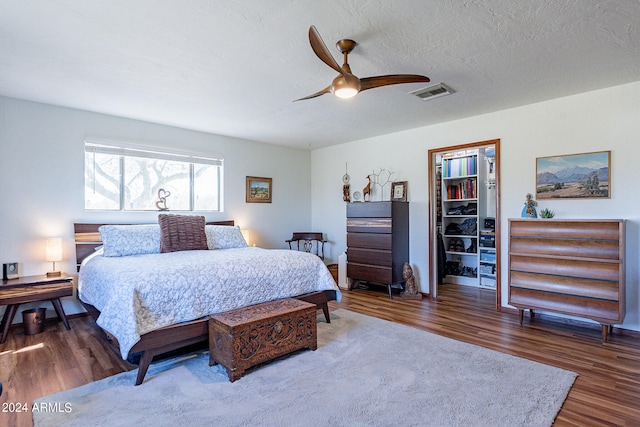 bedroom with ceiling fan, a textured ceiling, and dark hardwood / wood-style floors