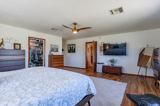 bedroom with a closet, a spacious closet, ceiling fan, and dark wood-type flooring