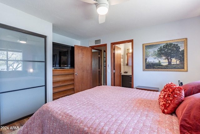 bedroom with dark hardwood / wood-style flooring, ceiling fan, and ensuite bath