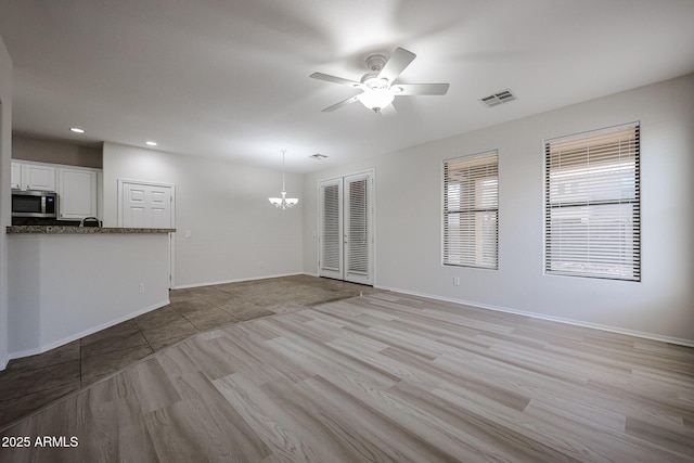45633 W Mountain View Rd, Maricopa, AZ 85139 - unfurnished living room with baseboards, visible vents, ceiling fan with notable chandelier, and light wood-style floors